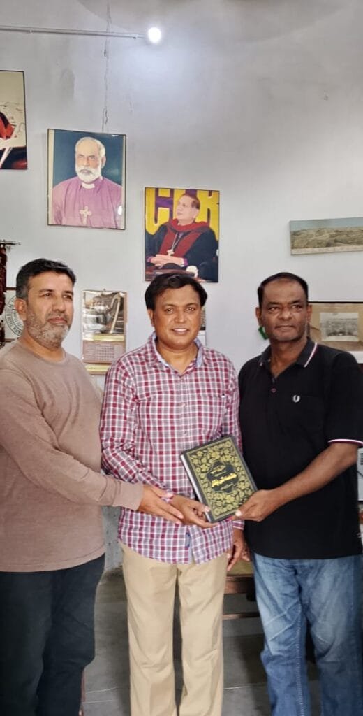 Mr. Shahzad Lawrence is receiving book from Elder Kamil Nasir and Rev. Inam