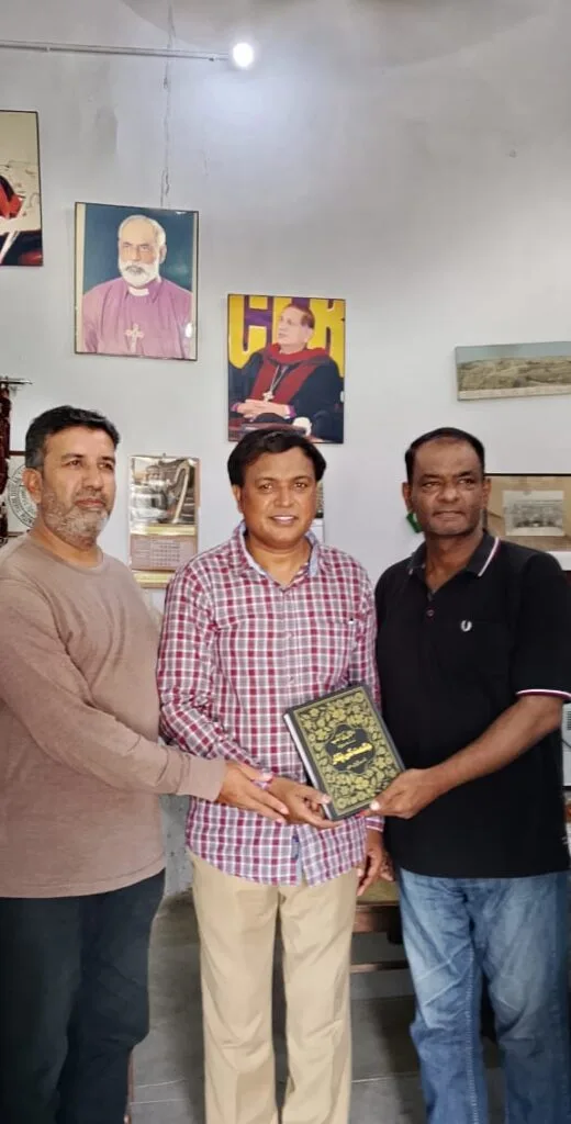 Mr. Shahzad Lawrence is receiving book from Elder Kamil Nasir and Rev. Inam